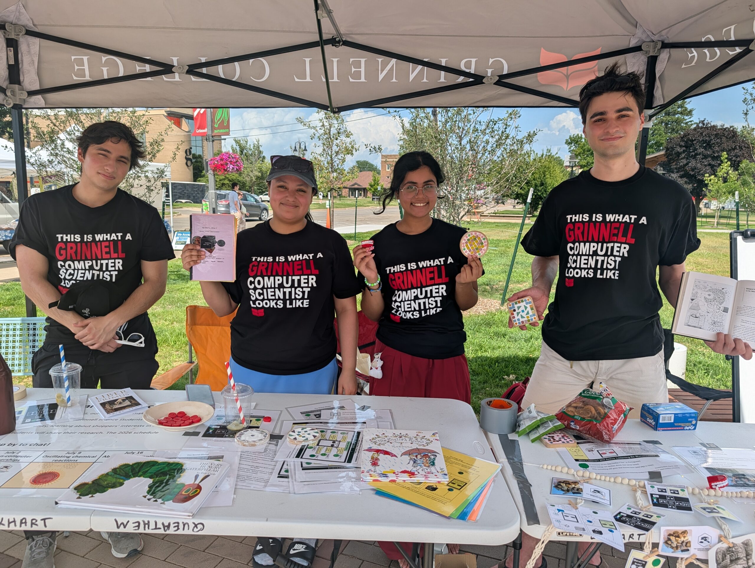 A team of four students standing behind a desk and presenting their research at the farmer's market